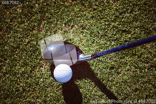 Image of top view of golf club and ball in grass