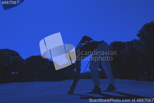 Image of golf player placing ball on tee