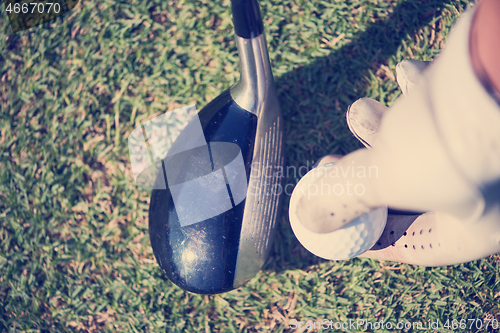 Image of golf player placing ball on tee