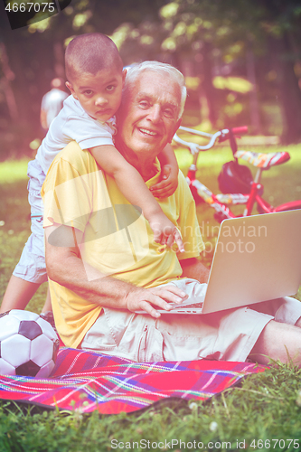 Image of grandfather and child using laptop