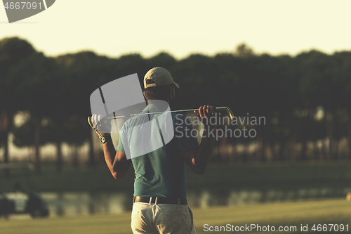 Image of golfer from back at course looking to hole in distance