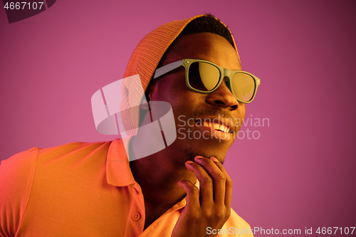 Image of Portrait of a happy young african american man smiling on black neon background