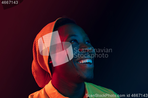 Image of Portrait of a happy young african american man smiling on black neon background