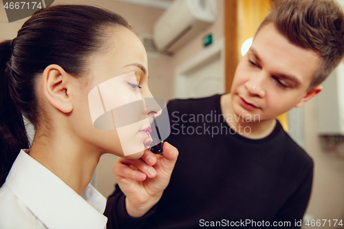 Image of Professional makeup artist working with beautiful young woman