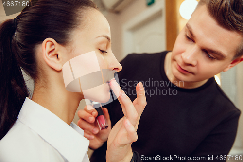 Image of Professional makeup artist working with beautiful young woman