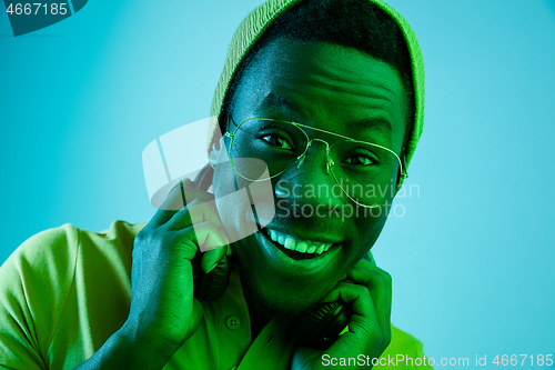 Image of Portrait of a happy young african american man smiling on black neon background