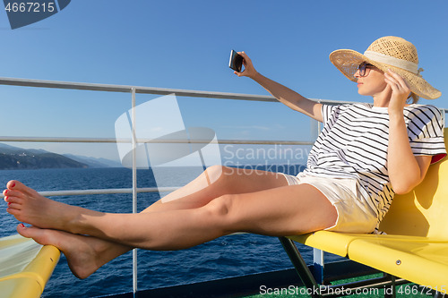 Image of Beautiful, romantic blonde woman taking selfie self portrait photo on summer vacations traveling by cruse ship ferry boat.