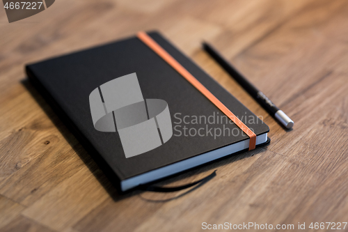 Image of Black business notebook and regular pencil on a vintage wooden desk