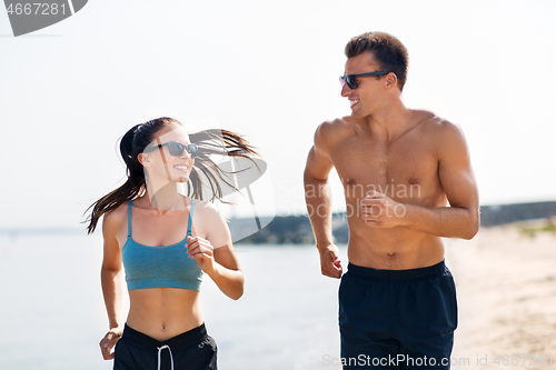 Image of couple in sports clothes running along on beach