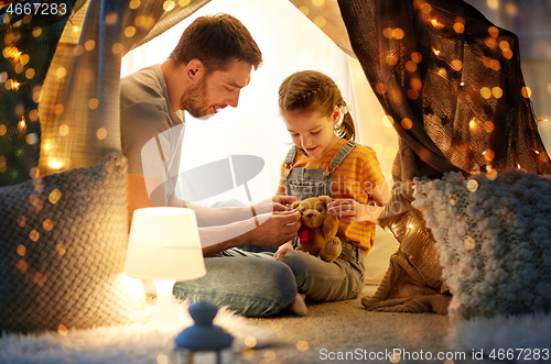 Image of happy family playing with toy in kids tent at home