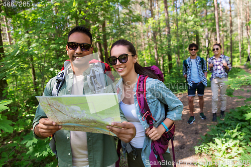 Image of friends with map and backpacks hiking in forest