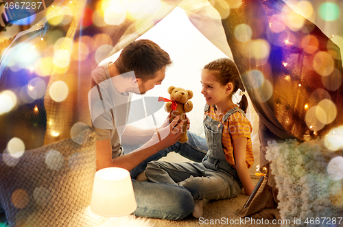 Image of happy family playing with toy in kids tent at home