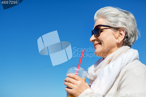 Image of senior woman drinking orange juice outdoors