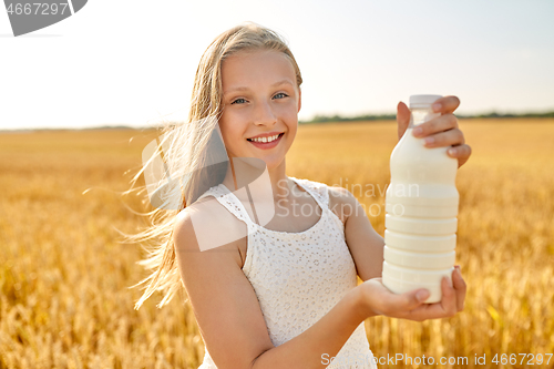 Image of happy girl with bottle of milk on cereal field