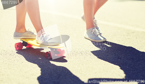 Image of feet of teenage couple riding skateboard on road