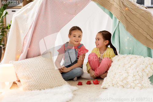 Image of little girl playing tea party in kids tent at home