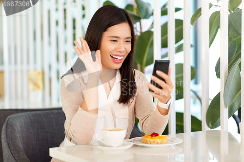 Image of woman having video call on smartphone at cafe