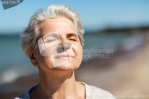 Image of portrait of senior woman enjoying sun on beach