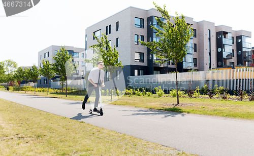 Image of young businessman riding electric scooter outdoors