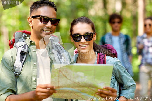 Image of friends with map and backpacks hiking in forest