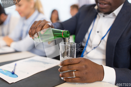 Image of businessman pouring water to glass at conference