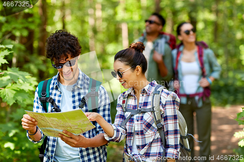 Image of friends with map and backpacks hiking in forest