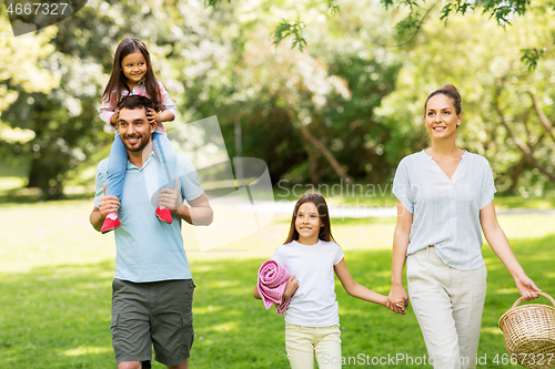 Image of family with picnic basket walking in summer park