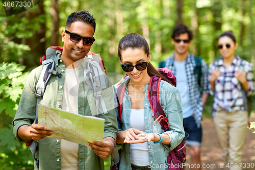 Image of friends with map and backpacks hiking in forest