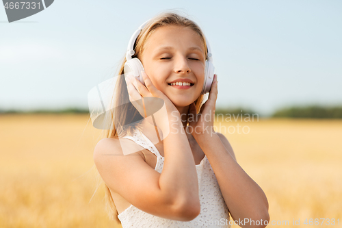 Image of happy girl in headphones on cereal field in summer