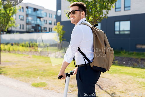 Image of businessman with backpack riding electric scooter