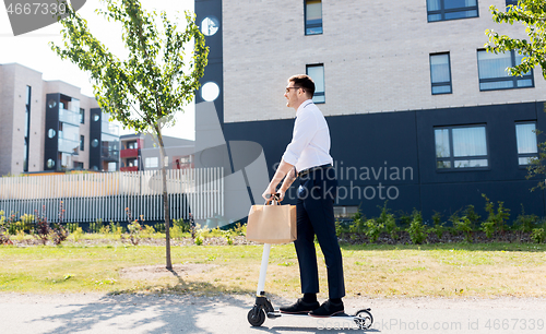 Image of businessman with takeaway lunch riding scooter