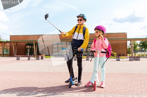 Image of happy school kids with scooters taking selfie