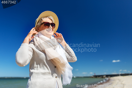 Image of happy senior woman in sunglasses and hat on beach