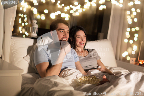Image of couple with popcorn watching tv at night at home