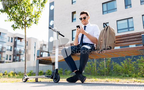 Image of businessman with smartphone, backpack and scooter