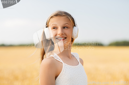 Image of happy girl in headphones on cereal field in summer