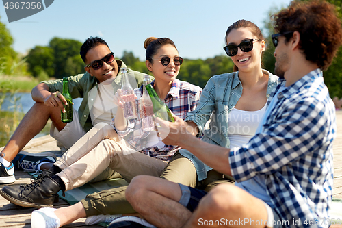 Image of friends drinking beer and cider on lake pier