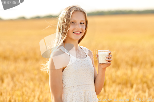 Image of happy girl with glass of milk on cereal field