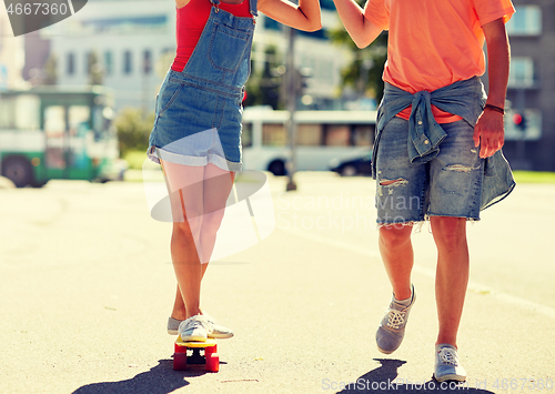 Image of teenage couple riding skateboard on city street