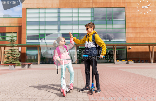 Image of school kids riding scooters and making high five