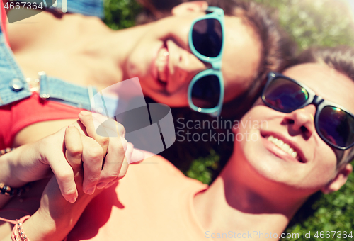 Image of happy teenage couple lying on grass at summer