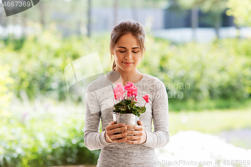 Image of young woman with cyclamen flowers at summer garden