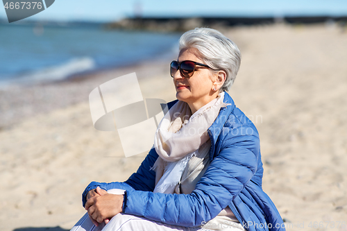 Image of happy senior woman in jacket on beach