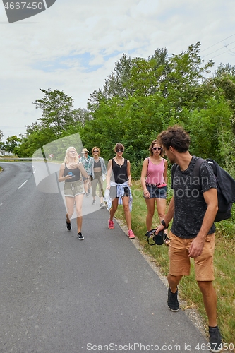 Image of Young group of friends walking by the road