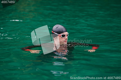 Image of triathlon athlete swimming on lake wearing wetsuit