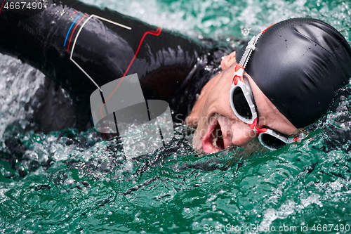 Image of triathlon athlete swimming on lake wearing wetsuit