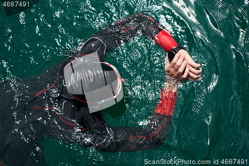Image of triathlon athlete swimming on lake setting smartwatch