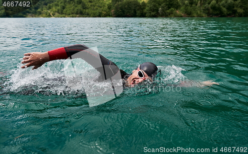 Image of triathlon athlete swimming on lake wearing wetsuit