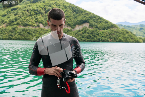 Image of triathlon athlete getting ready for swimming training on lake