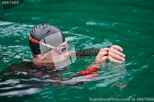 Image of triathlon athlete swimming on lake setting smartwatch